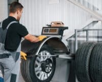 Fixing the tire. Man in uniform is working in the auto service